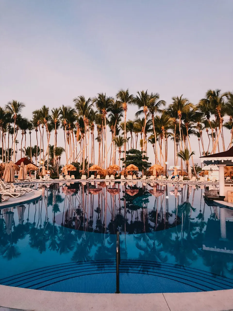 Pool mit Palmen in warmer Abendstimmung