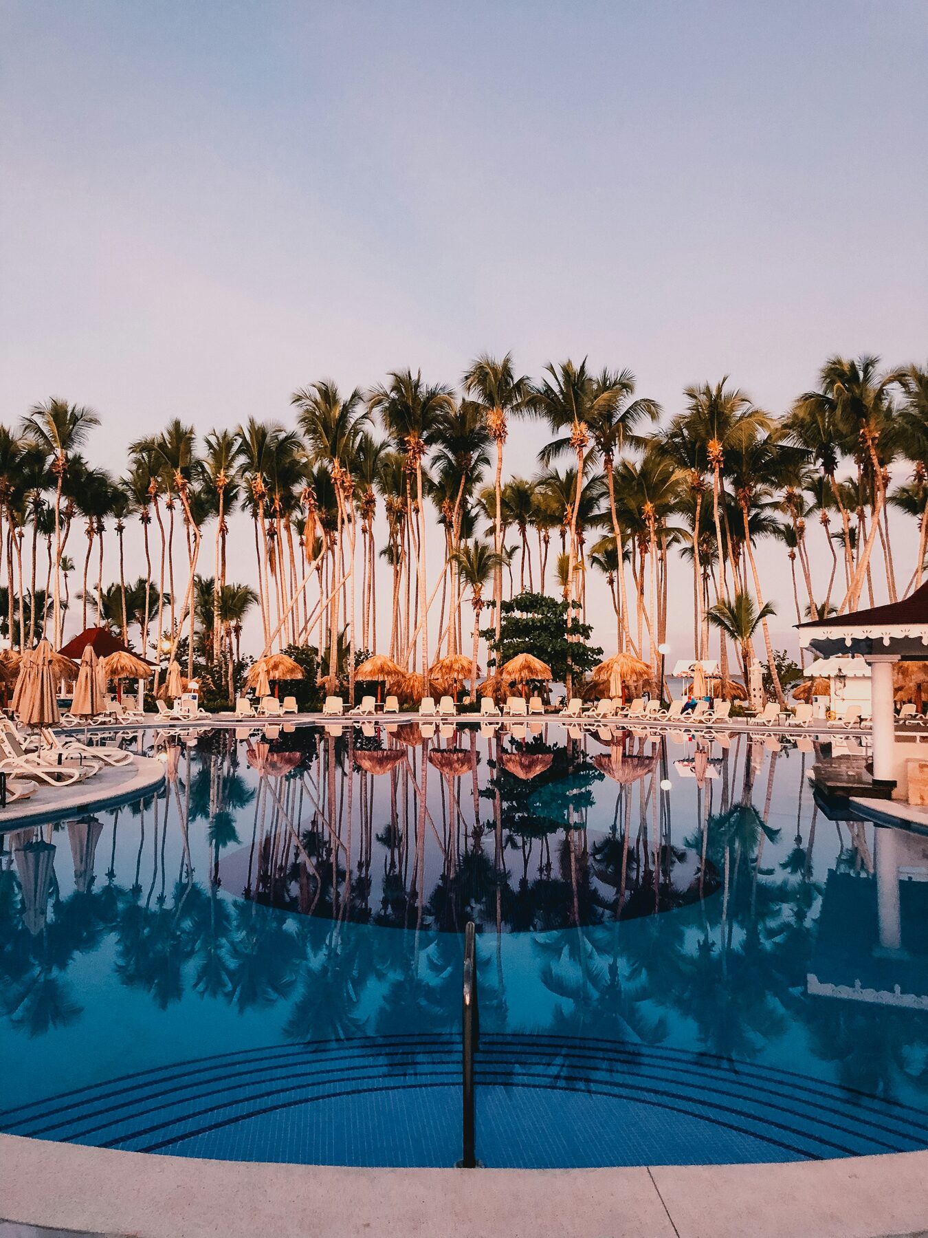 Pool mit Palmen in warmer Abendstimmung